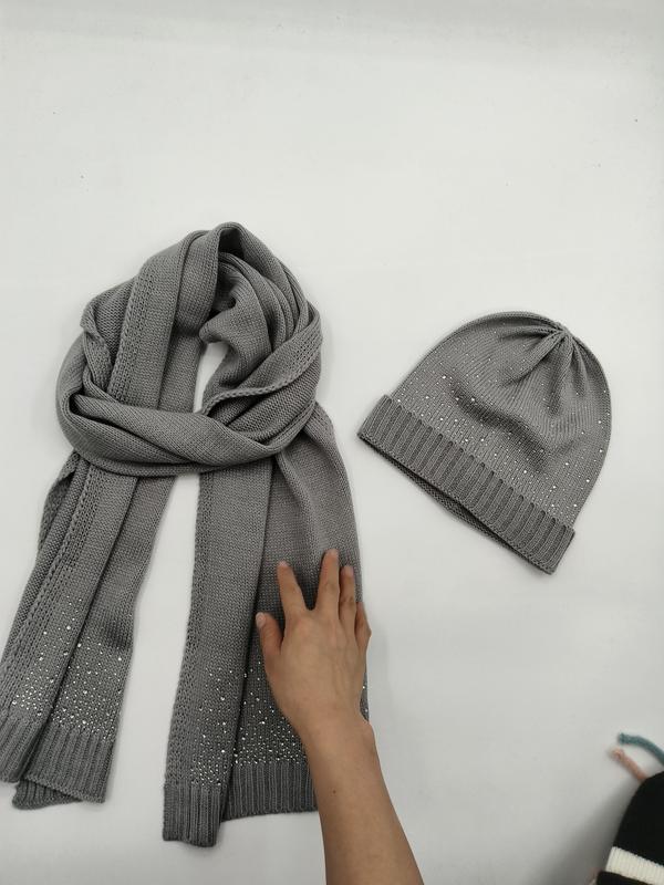 Graues Strickschal und Beanie-Set mit silbernen Strasssteinen auf weißer Fläche flach ausgelegt