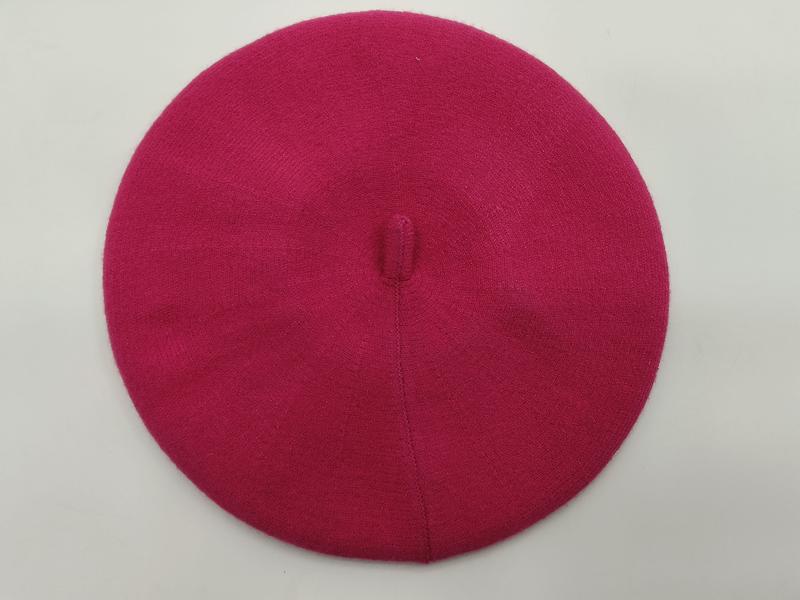 Pinkfarbenes Damenbarett aus feiner Strickwolle mit Knopf an der Spitze, Draufsicht auf weißem Hintergrund