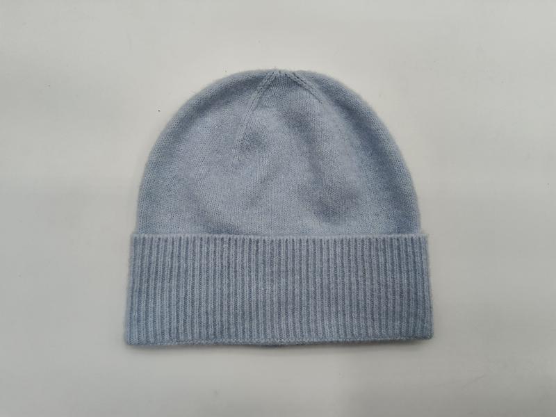 Weiche hellblaue Strickmütze mit breitem umgeklapptem Rippbund, flach auf weißem Hintergrund liegend, nahtloser Mützenabschluss