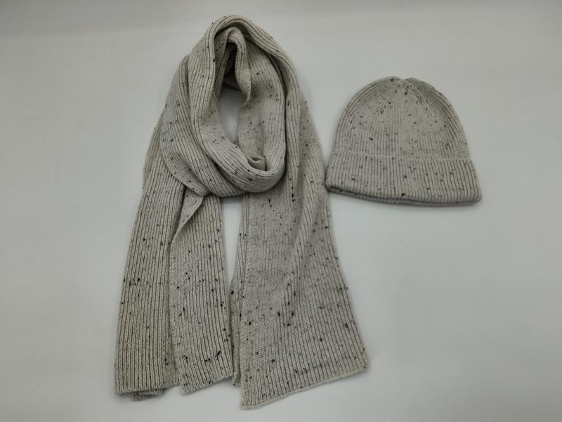 Hellgrauer Rippstrickschal und passende Beanie mit dunklem Sprenkel-Muster nebeneinander auf weißem Hintergrund