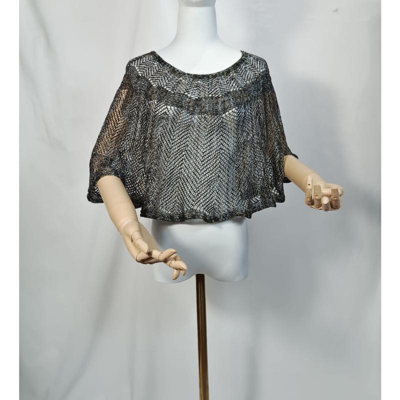 Kurzgeschnittener Metallicponcho in Silber und Schwarz auf weißer Schaufensterpuppe, weite Fledermausärmel, gelenkartige Holzarme