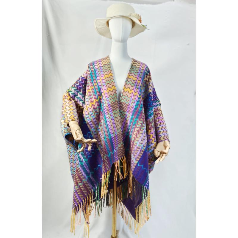 Schaufensterpuppe in farbigem Webponcho mit Chevron-Muster, überlangen Fransenenden und breitem Sonnenhut, Studiofoto
