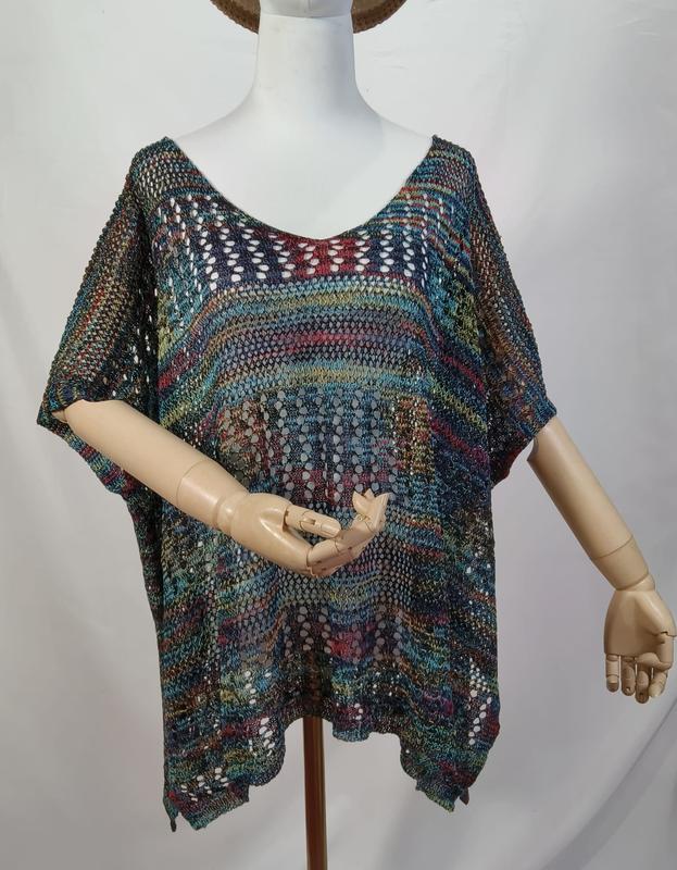 Buntes Boho-Häkelponcho mit Kurzarm auf einer Schneiderpuppe, mit Farbakzenten in Petrol, Rot und Gold