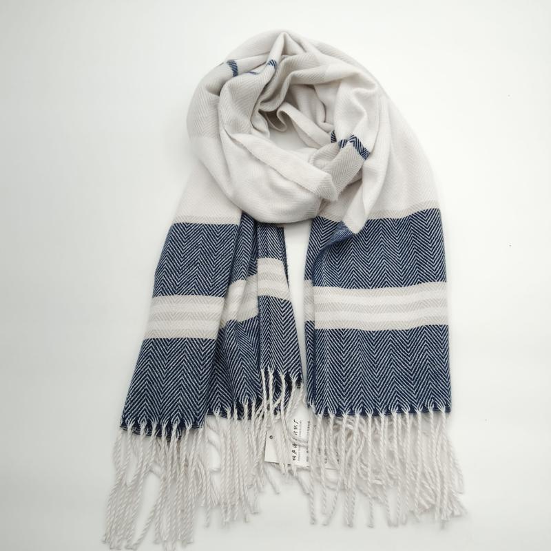 Gewebter Schal in Marineblau und Creme mit markantem Fischgrat-Muster, breiten Streifen und Quasten-Fransen, aufgerollt auf weißem Hintergrund
