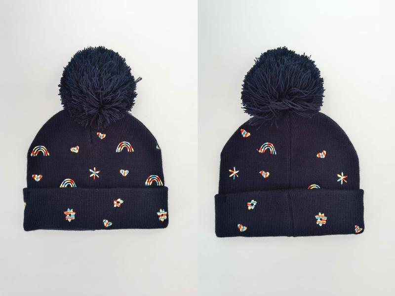 Marine-blaue Strickmütze mit großem Bommel, farbenfrohen gestickten Regenbögen, Herzen, Sternen und Blümchen von vorne und seitlich