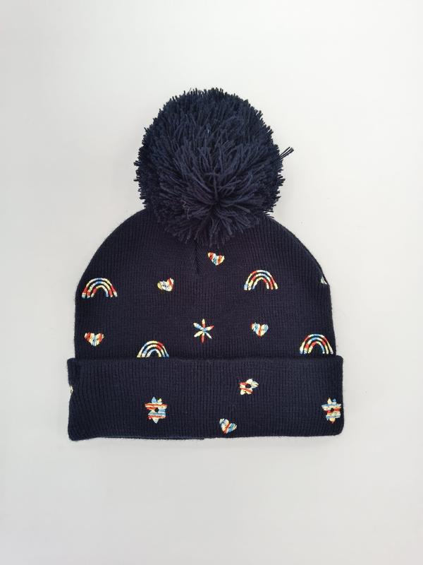 Marine-blaue gerippte Strickmütze mit großem Pompon und bunten gestickten Motiven wie Regenbogen, Herz und Stern