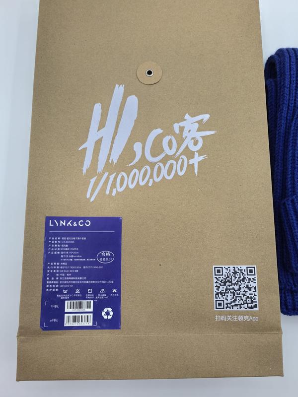 Marineblaues Grob-Strickset aus Wollschal und Beanie-Mütze in einer nachhaltigen Kraftpapier-Umschlagtasche mit Produktetikett