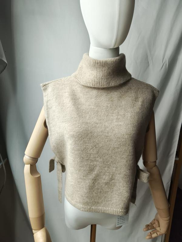 Cremefarbene ärmellose Rollkragen-Strickweste mit seitlichen Bindebändern auf einer Schneiderpuppe