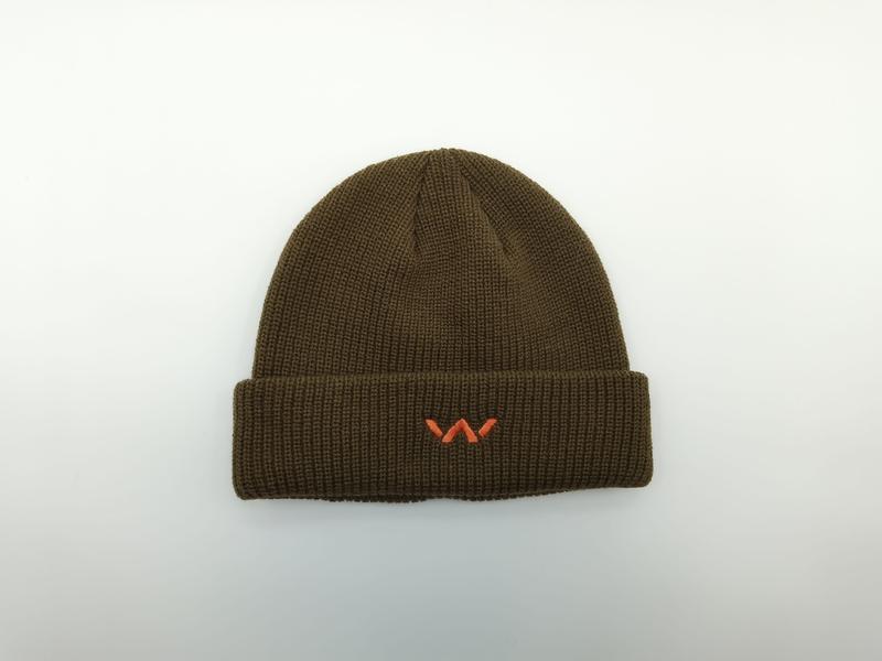 Olivgrüne Strickmütze mit Umschlagbündchen und kleinem orangenem Stickerei-Emblem, flach auf weißem Hintergrund fotografiert