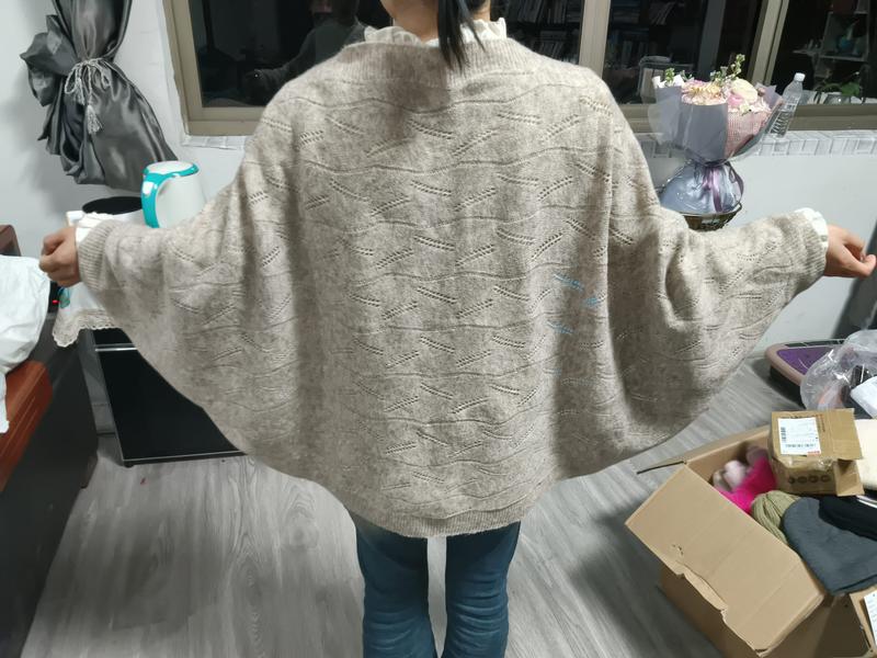 Frau von hinten in übergroßem beigem Fledermausärmel-Pullover mit Rauten-Pointelle-Muster, kombiniert mit blauen Jeans