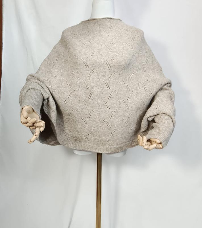 Weiter cremefarbener Ajour-Strickpullover mit ausgestellten Ärmeln und Rautenmuster auf Schneiderpuppe mit Holzkünstlerhänden