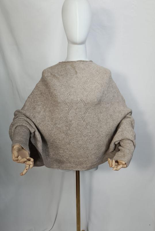 Rückenansicht eines weiten cremefarbenen Ajour-Strickpullovers mit Ballonärmeln und Rippbündchen auf weißer Schneiderpuppe