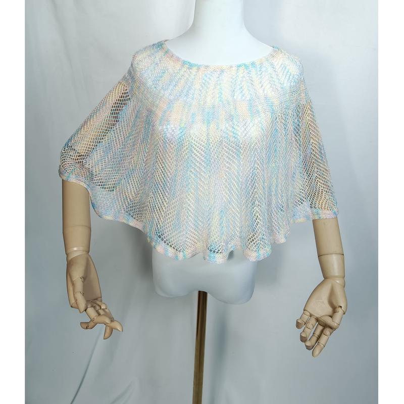 Weiße Schaufensterpuppe mit halbtransparentem Netzponcho in zarten Pastelltönen Hellblau, Pfirsich und Elfenbein, locker drapiert