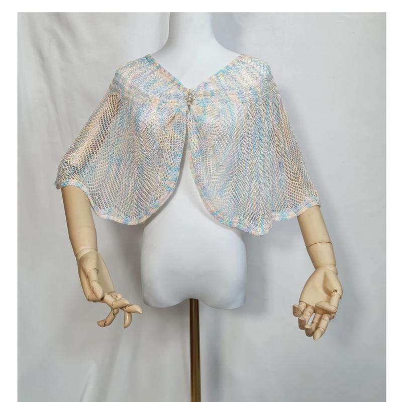 Offener Strickumhang in zartem Blau, Rosa und Creme mit glitzernder Strassbrosche auf weißer Schneiderpuppe