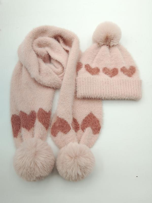 Pinkes flauschiges Winter-Strickset aus Mütze und Schal mit Rosen-Herz-Jacquardmuster und Kunstfell-Bommel-Verzierung auf weißem Hintergrund