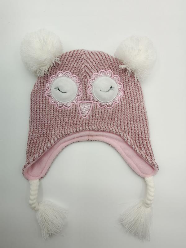 Rosa grob gestrickte Kinderwintermütze mit aufgesticktem Eulengesicht, weißen Bommeln, Ohrklappen und geflochtenen Quasten