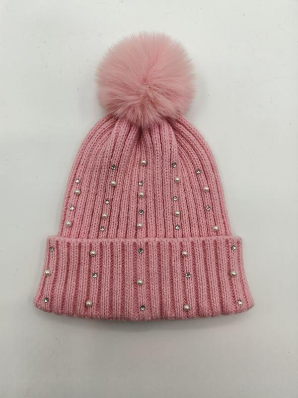 Rosa Rippenstrickmütze mit flauschigem Kunstfell-Bommel sowie Perlen- und Kristall-Strassstein-Verzierungen auf weißem Hintergrund