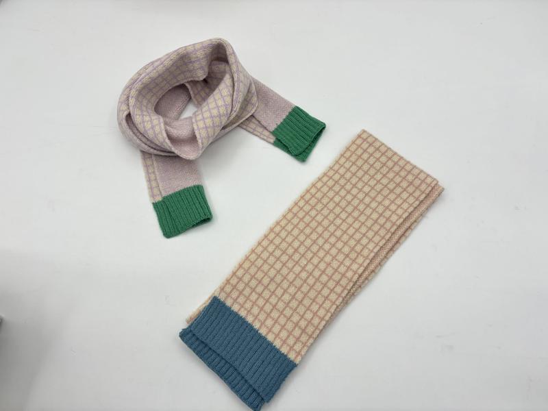 Zwei karierte Strickschals auf weißem Untergrund: lavendelfarbener Schal zur Schlaufe gelegt mit grünem Bündchen, beige-karierter Schal gefaltet mit blauem Rippabschluss