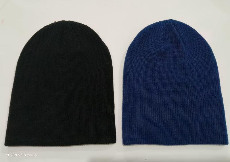Zwei schlichte Slouchy-Beanies nebeneinander in Schwarz und Royalblau, gerippte Struktur ohne Bund, Studioaufnahme