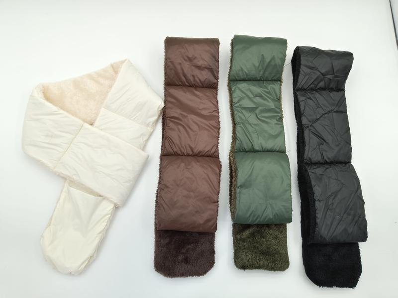 Vier gesteppte Puffer-Schals mit Kunstfell-Innenfutter nebeneinander in Creme, Braun, Olivgrün und Schwarz auf hellem Hintergrund