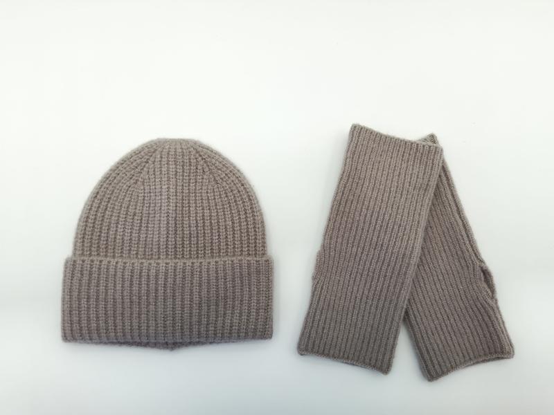 Taupefarbenes Winter-Set aus gerippter Strickmütze und passenden fingerlosen Handschuhen, flach auf weißem Hintergrund