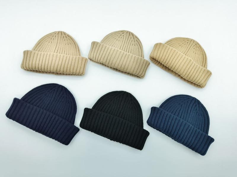 Sechs gerippte Umschlagrand-Beanies in zwei Reihen angeordnet – in den Farben Beige, Dunkelblau, Schwarz und Stahlblau auf weißem Untergrund