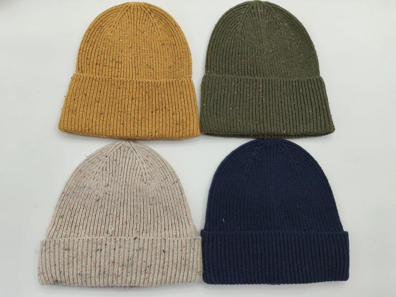 Vier Rippenstrick-Beanies in Senfgelb, Olivgrün, Haferflocken-Melange und Marineblau, flach auf weißem Untergrund