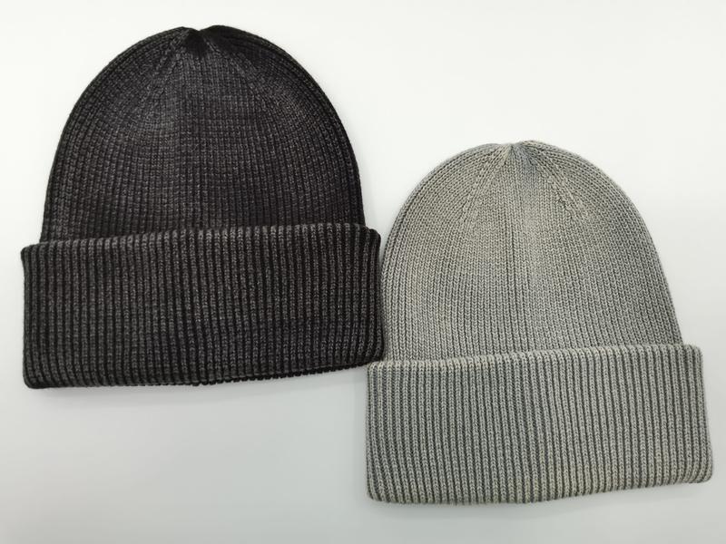 Zwei Rippenstrickmützen mit Umschlagrand nebeneinander – eine in dunklem Anthrazit und eine in hellem Grau auf weißem Hintergrund
