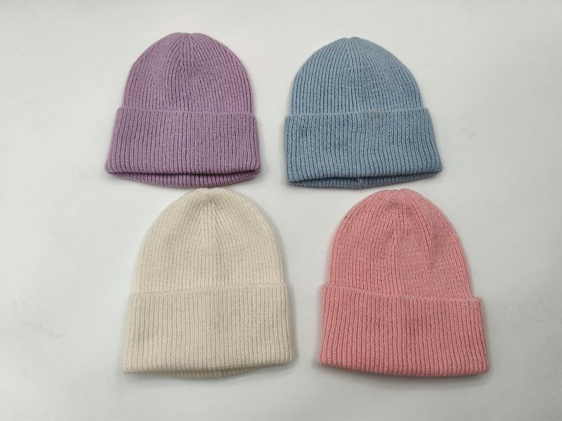 Vier zarte Rippstrickmützen in Pastell-Lavendel, Himmelblau, Vanille und Blassrosa nebeneinander auf weißer Fläche