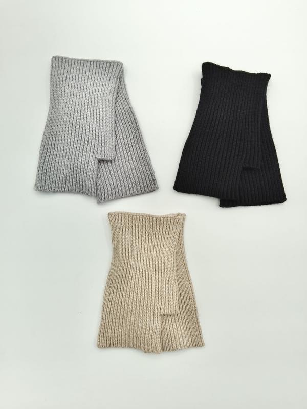 Drei fingerlose Rippstrickhandschuhe in Hellgrau, Schwarz und Beige flach ausgelegt auf weißem Hintergrund