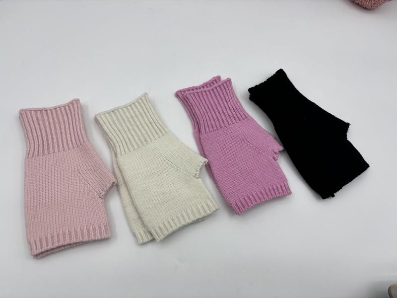 Vier fingerfreie Rippenstrickhandschuhe in Rosa, Creme, Flieder und Schwarz nebeneinander auf hellem Untergrund