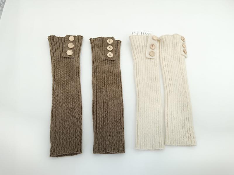 Zwei Paare gerippter Strick-Beinstulpen mit Holzknöpfen am oberen Rand, eine in Taupe und eine in Creme, flach photographiert auf weißem Untergrund