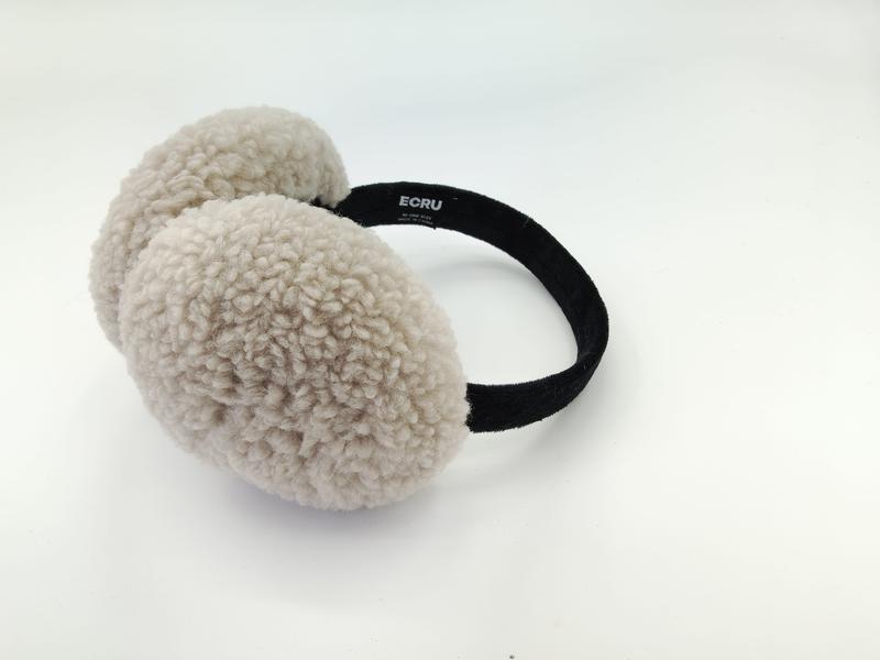 Cremefarbene Ohrenwärmer aus flauschigem Sherpa-Fleece mit schmalem schwarzen Haarband, auf hellem Hintergrund