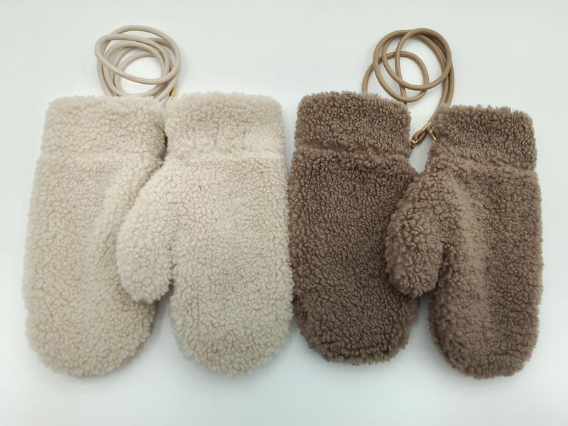 Zwei Paar flauschige Plüsch-Winterhandschuhe in Weißcreme und Graubraun, jeweils mit Leder-Haltekordel am Handgelenk, auf hellem Hintergrund