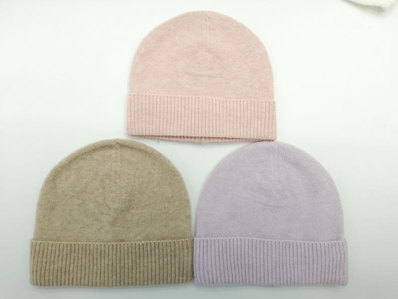 Drei Strickmützen mit Rippenbündchen in Altrosa, Sandbeige und Lavendel, flach auf weißem Untergrund angeordnet