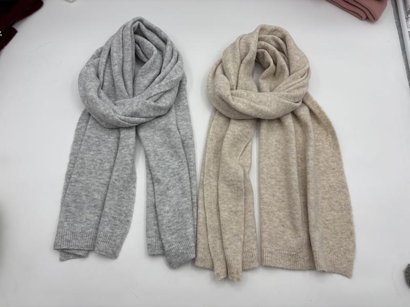 Zwei weiche Strickschals flach übereinandergelegt – einer in Hellgrau, einer in Beige, mit gerippten Enden und kuscheligen Strickdetails