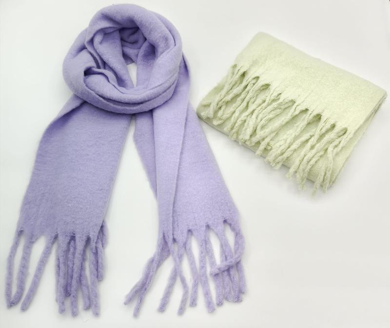 Zwei weiche Flauschschals mit Fransenenden: einer in Lavendel offen geloopt, einer in Mintgrün gefaltet, auf weißem Hintergrund
