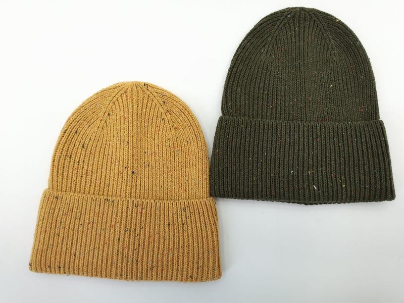 Zwei Rippenstrick-Beanies mit Umschlagbündchen und bunten Fleckdetails in Senfgelb und Olivgrün, Draufsicht auf weißem Hintergrund