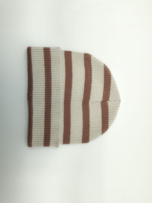 Flach aufgelegte Rippenstrickmütze mit abwechselnden Streifen in Creme und Sandbraun, umgeklapptes Bündchen auf weißem Hintergrund