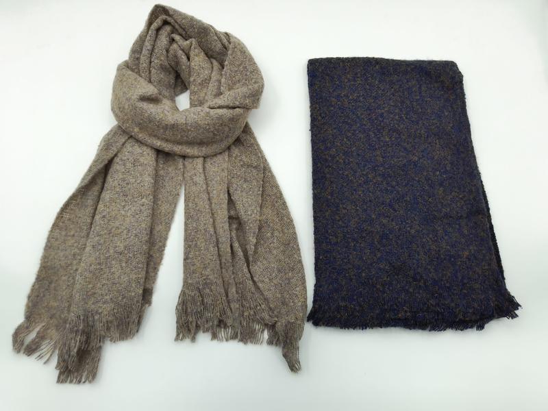 Zwei gewebte Schals mit Fransenrand nebeneinander: ein drapierter Taupe-Melange-Schal und ein gefalteter Marineblau-Tweedschal auf weißem Hintergrund